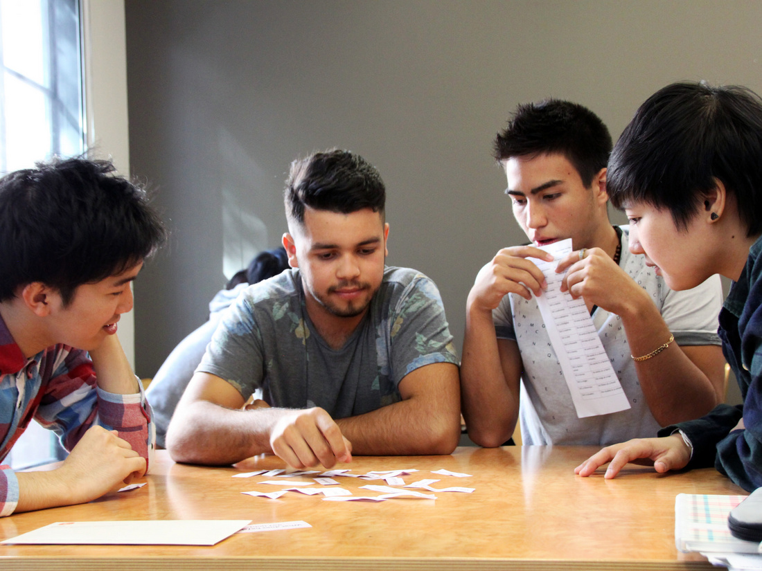 Bild: ILSC Education Group, Lizenz: CC BY-NC-ND 2.0 Vier junge Menschen sitzen an einem Tisch und diskutieren miteinander. Sie schauen auf eine Sammlung von Karten und Notizen, während sie Ideen austauschen. Ihr Fokus liegt auf der Zusammenarbeit und den Informationen auf dem Tisch.