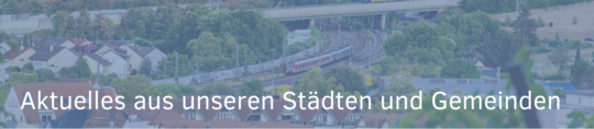 Eine panoramische Ansicht einer Stadt mit einem Zug, der durch eine grüne Landschaft fährt. Am oberen Bildrand steht der Text: „Aktuelles aus unseren Städten und Gemeinden“. Die Umgebung zeigt Wohngebäude und Bäume.