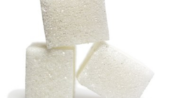 Three white sugar cubes are stacked in a leaning arrangement, showcasing their square shape and crystalline texture. The image focuses on the simplicity and purity of the sugar.