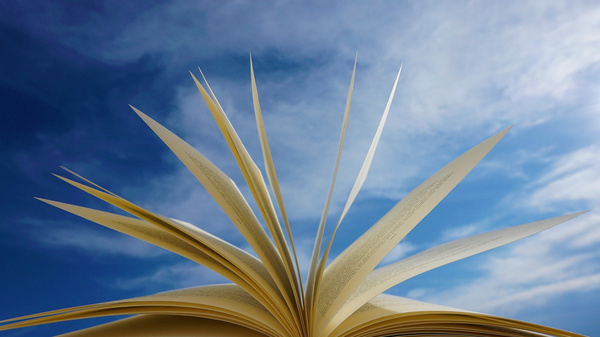 An open book with pages fanned out against a blue sky with clouds. The book's pages are gently lifted, suggesting the potential for new ideas and stories.