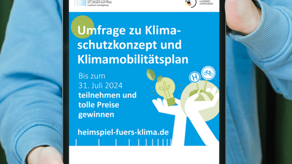 Eine Person hält ein Tablet, auf dem eine Aufforderung zur Teilnahme an einer Umfrage zum Klimaschutzkonzept und Klimamobilitätsplan angezeigt wird. Die Umfrage läuft bis zum 31. Juli 2024, und es gibt die Möglichkeit, tolle Preise zu gewinnen. Webseite: heimspiel-fuers-klima.de.