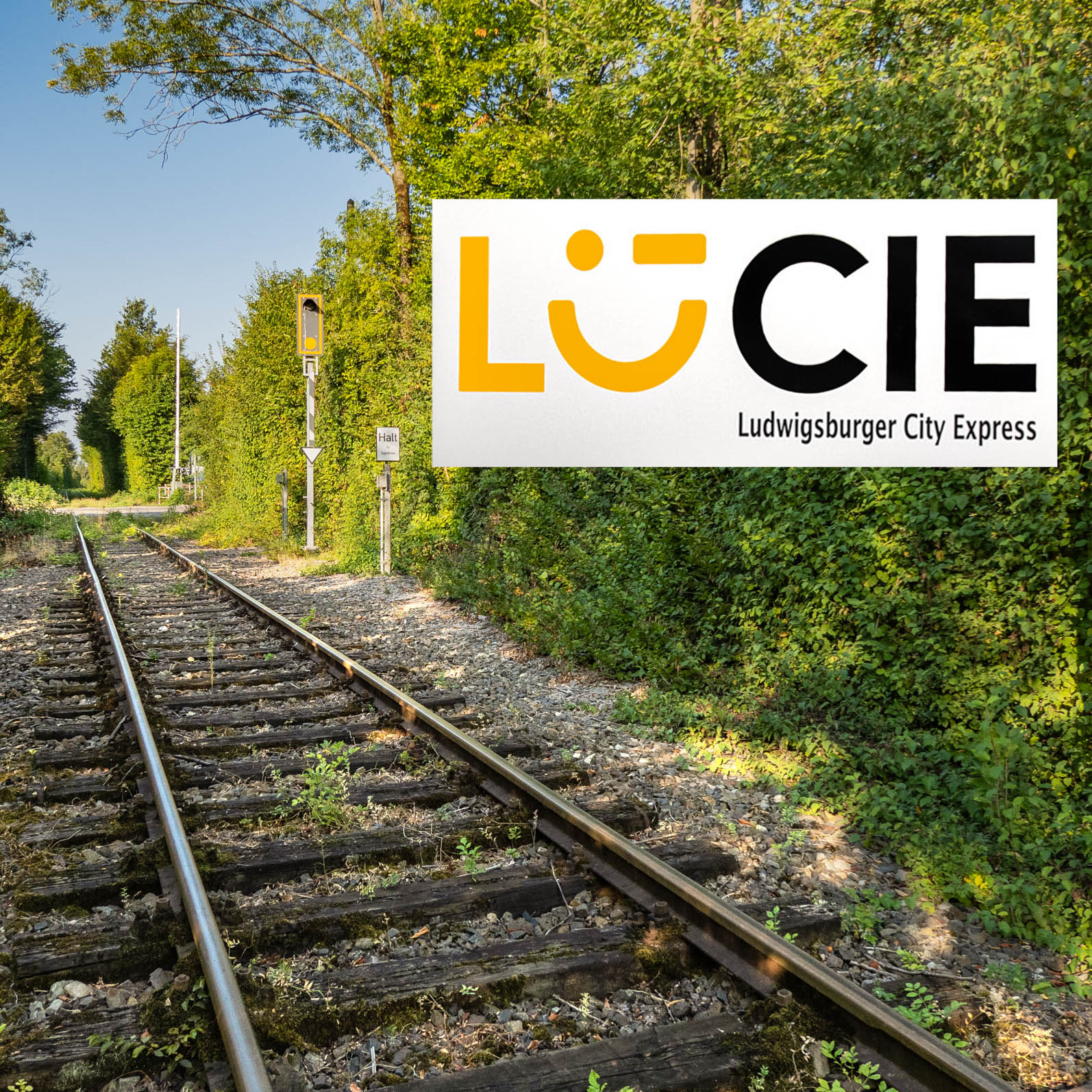Railroad tracks on the left, a sign for the Lucie light rail on the right