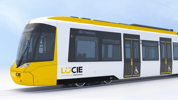 Ein moderner Straßenbahnwagen mit einer gelben und weißen Farbgestaltung. Die Vorderseite zeigt eine große Windschutzscheibe, während auf der Seite das Logo „LUCIE“ und ein Symbol für Barrierefreiheit zu sehen sind. Die Bahn steht auf einem Schienennetz vor einem hellen, nebligen Hintergrund.
