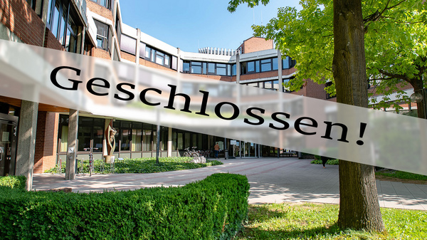 Ein Gebäude mit modernen Fenstern und einer grünen Hecke im Vordergrund. Ein Banner mit der Aufschrift "Geschlossen!" überlagert das Bild, was darauf hinweist, dass der Ort nicht zugänglich ist. Es sind Teilbereiche einer Landschaft und eine Skulptur sichtbar.