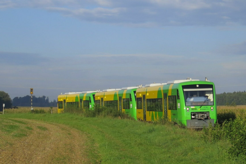 Die Strohgäubahn mit ihren grün-gelben Wagons fährt auf Schienen gesäumt von Wiesen und Feldern.