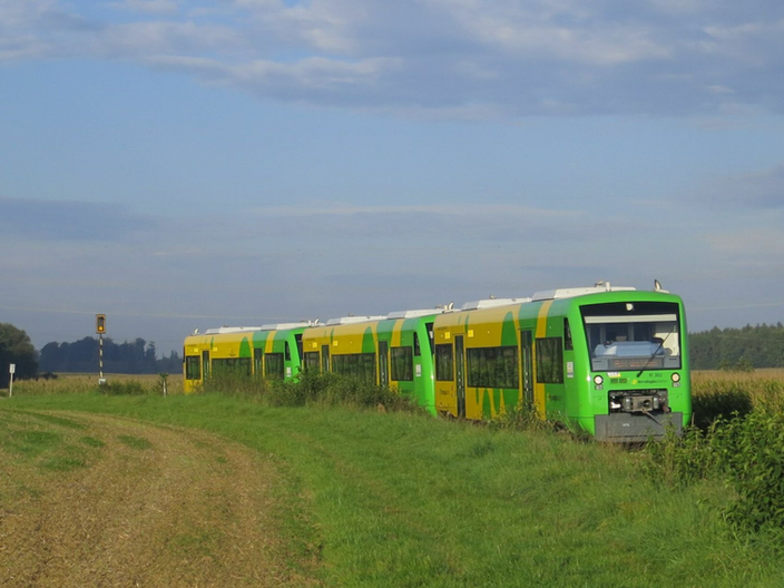 Die Strohgäubahn mit ihren grün-gelben Wagons fährt auf Schienen gesäumt von Wiesen und Feldern.