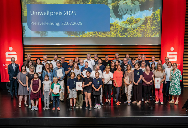 Verleihung des Umweltpreises 2025 Gruppenbild der Preisträgerinnen und Preisträger des Umweltpreises 2025. Die Teilnehmer halten teilweise ihre Urkunden in den Händen. Im Hintergrund ist ein Bildschirm mit dem Titel „Umweltpreis 2025“ und dem Datum „22.07.2025“ sichtbar, flaniert von den Kreissparkassenbannern.