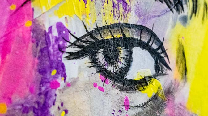Das Bild zeigt eine künstlerische Nahaufnahme eines Auges, umgeben von lebhaften, bunten Farbspritzern in Lila, Gelb und Pink. Die Details des Auges sind gut ausgearbeitet, während der Hintergrund aus abstrakten Farbmustern besteht, die eine dynamische und emotionale Atmosphäre schaffen.