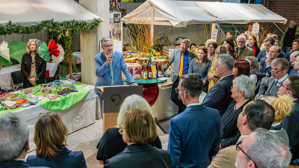 Landrat Dietmar Allgaier steht hinter einem Rednerpult mit Mikrophon in der Hand und begrüßt die umstehenden Menschen