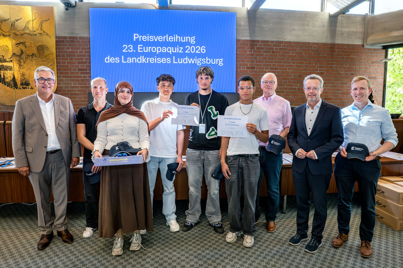 Gruppenfoto von Teilnehmern der Preisverleihung des 23. Europaquiz 2026 des Landkreises Ludwigsburg. Die Gewinner halten Urkunden und tragen schwarze Kappen. Im Hintergrund steht ein Bildschirm mit dem Titel der Veranstaltung. Es sind insgesamt sieben Personen zu sehen, darunter auch zwei Frauen.