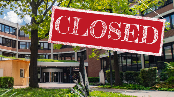 Ein Gebäude mit einem Schild, das "CLOSED" (geschlossen) anzeigt, hängt über dem Eingang. Die Umgebung besteht aus einem grünen Garten mit Bäumen und Sträuchern. Es ist sonnig und der Bereich wirkt ruhig.