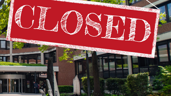 Ein Gebäude mit einem Schild, das "CLOSED" (geschlossen) anzeigt, hängt über dem Eingang. Die Umgebung besteht aus einem grünen Garten mit Bäumen und Sträuchern. Es ist sonnig und der Bereich wirkt ruhig.