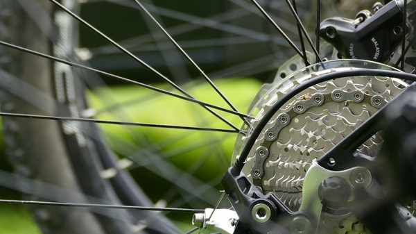 Dettaglio della ruota di una bicicletta, focale sulla parte posteriore con il sistema di cambio. Mostra i raggi, il pacco pignoni e il deragliatore, evidenziando l'ingegneria e la meccanica del ciclismo.