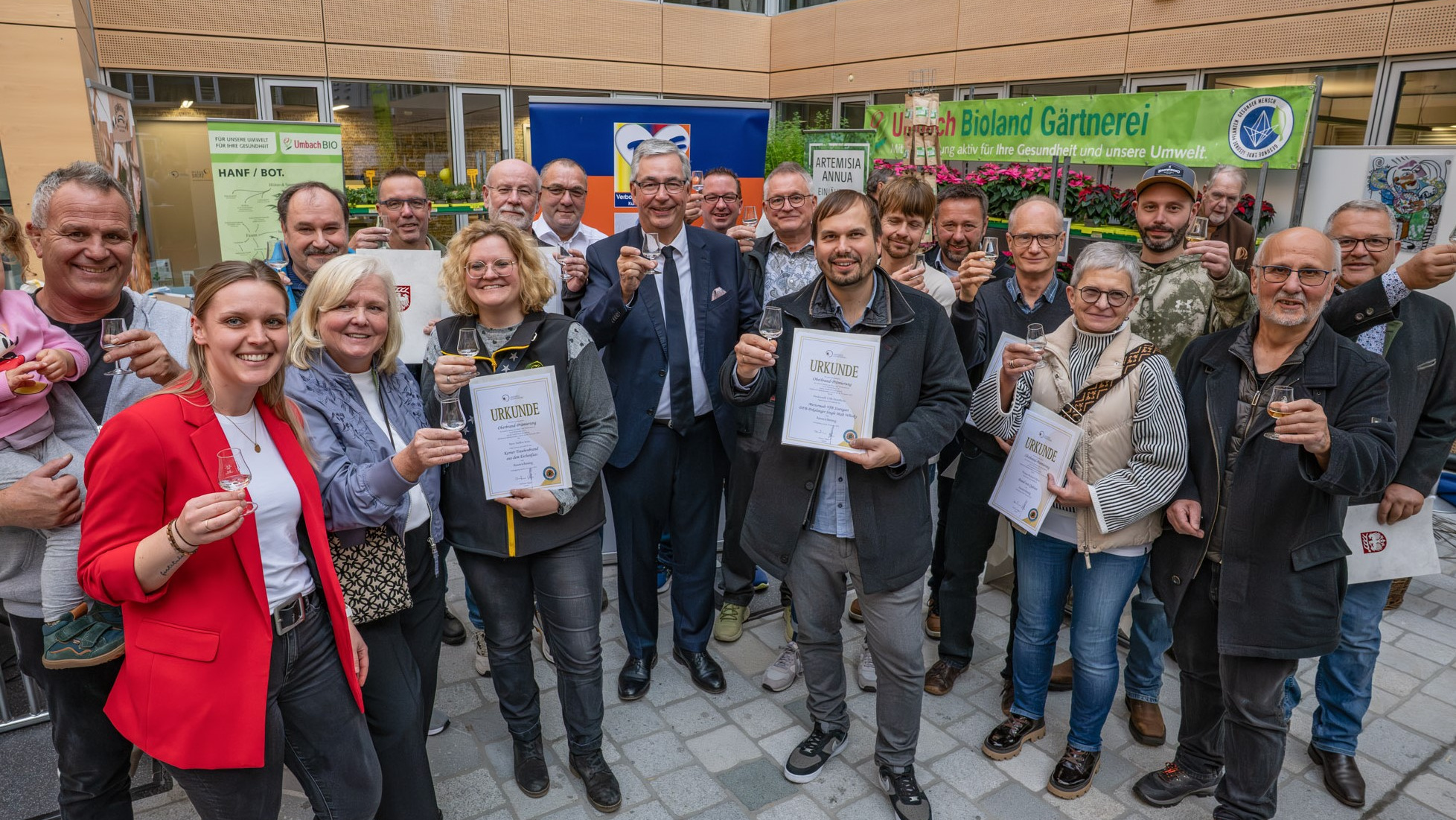 Personen stehen im Halbkreis mit Urkunden in der Hand