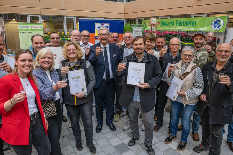 Personen stehen im Halbkreis mit Urkunden in der Hand