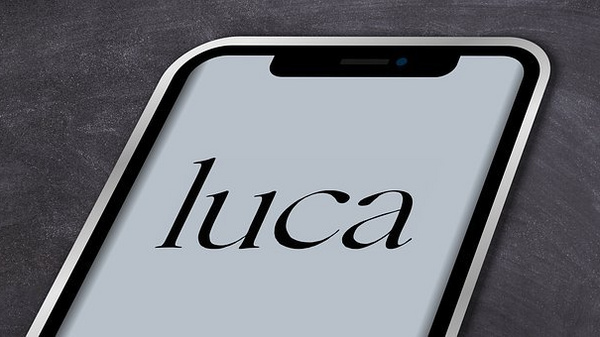 A smartphone screen displays the word "luca" in an elegant, stylized font against a light gray background. The phone is shown at an angle, highlighting its sleek design.