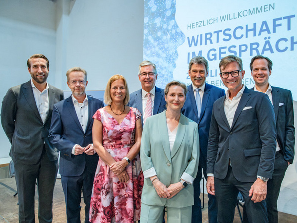 23.07.2024 - Wirtschaft im Gespräch in der Alten Kelter Benningen Ein Gruppenevent mit acht Personen, die sich lächelnd vor einer Präsentationsleinwand versammelt haben. Der Hintergrund zeigt den Text „Herzlich Willkommen Wirtschaft im Gespräch“. Die Menschen tragen formelle Kleidung und scheinen an einem geschäftlichen Austausch interessiert zu sein.