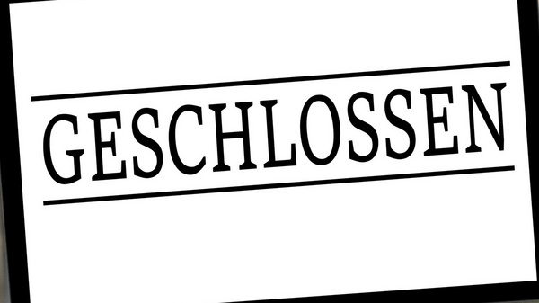 Ein Schild hängt an der Tür und zeigt das Wort "GESCHLOSSEN" in großen Buchstaben. Das Schild weist darauf hin, dass der Zutritt zum Geschäft nicht möglich ist.