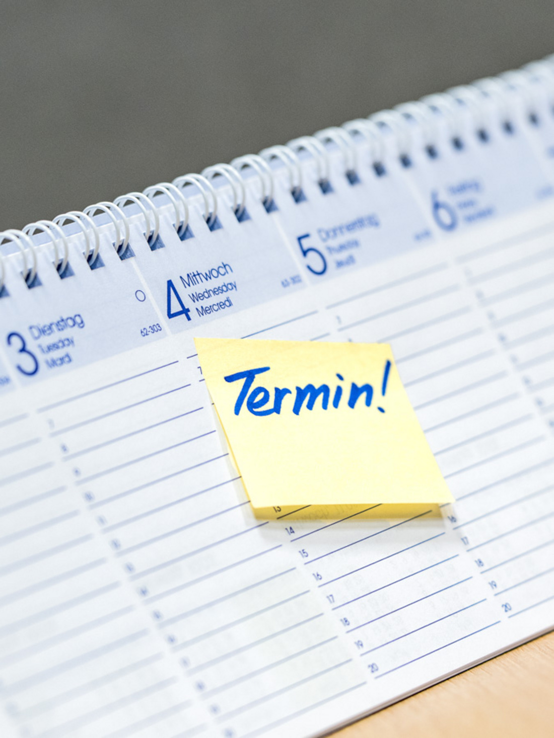 Terminankündigung Ein aufgeschlagener Kalender zeigt eine gelbe Haftnotiz mit der Aufschrift "Termin!". Der Fokus liegt auf der Terminankündigung.