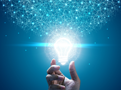 Eine Hand hält eine leuchtende Glühbirne, aus der eine Vielzahl von funkelnden, blauen Netzwerken strömt. Das Bild symbolisiert kreative Ideen und innovative Gedanken.