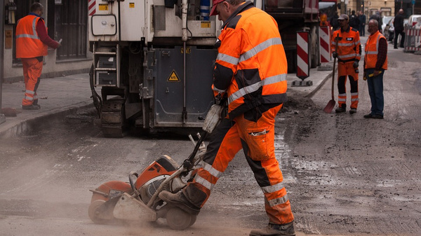 Bauarbeiter schneidet mit einer Steinsäge den Asphalt einer Straße