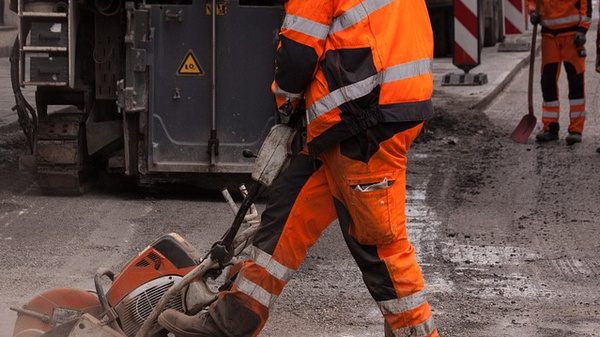 Bauarbeiter schneidet mit einer Steinsäge den Asphalt einer Straße