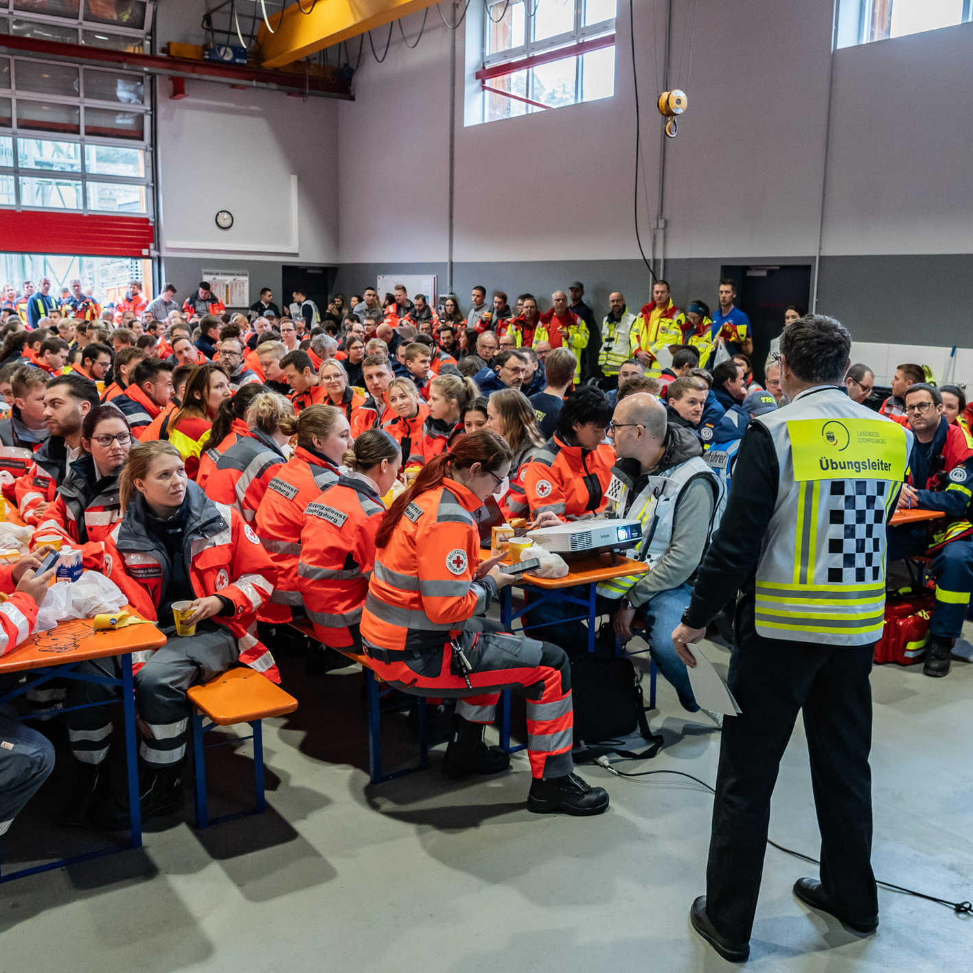 Feuerwehrleute sitzen auf Bänken in einer Halle
