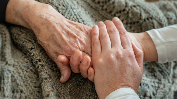 Una mano più giovane stringe amorevolmente una mano più vecchia.
