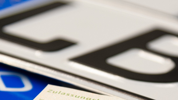 The image features various vehicle license plates, prominently displaying the letters "LB" and the letter "D," along with a vehicle registration document in a green color. The documents and plates are arranged closely together, emphasizing their importance in vehicle identification.