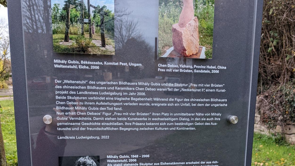 A dark information panel displays images of two sculptures. The left features a tall, abstract wooden sculpture, while the right showcases a stone figure. Below, text provides details about the artists and their work, along with a short description of the art installation context.