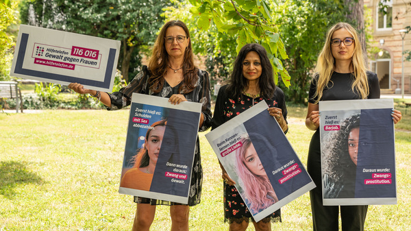 Cynthia Schönau, déléguée à l'égalité, le Dr Uschi Traub, responsable du département Promotion de la santé et Planification sanitaire, et Pauline Höll, étudiante du cursus en alternance « Gestion d'entreprise - Gestion de la santé », brandissent des affiches contre la traite des êtres humains.