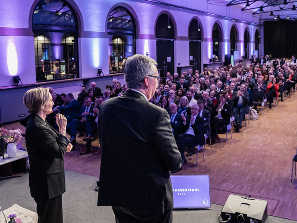 24.01.2025 - Neujahrsempfang im Reithaus Ludwigsburg Eine Veranstaltung in einem großen Saal ist zu sehen, in dem zahlreiche Menschen auf Stühlen sitzen. Im Vordergrund stehen zwei Personen, die miteinander sprechen, während das Publikum applaudiert. Die Atmosphäre wirkt festlich und aufmerksam.