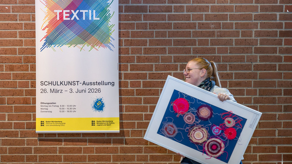 A woman carries a framed picture under her arm. The exhibition poster "Textile" hangs in the background.