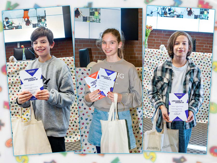 Drei Kinder stehen in einer Reihe und halten stolz ihre Urkunden in den Händen. Sie lächeln und tragen jeweils eine Umhängetasche. Im Hintergrund ist eine bunte Dekoration zu erkennen, die die festliche Atmosphäre unterstreicht.