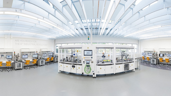 A spacious, modern laboratory filled with several workstations and advanced machinery. The design features bright lighting and a clean layout, emphasizing a focus on technology and innovation in industrial applications.