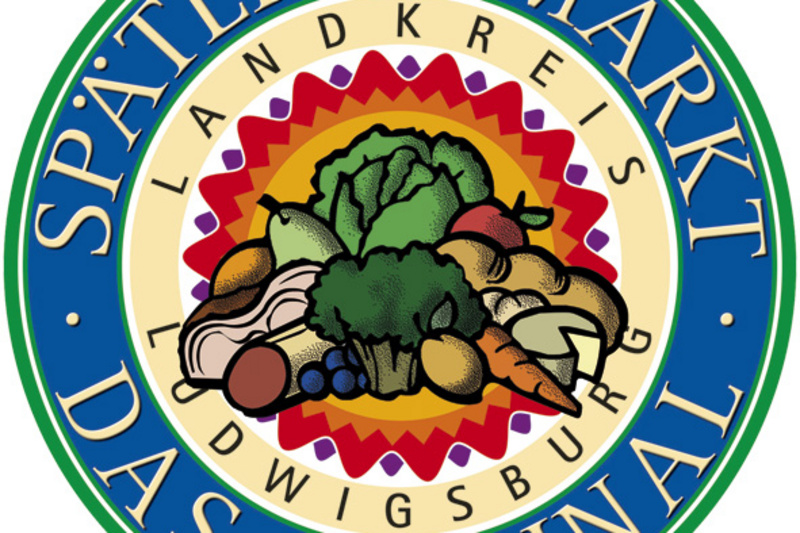 Rundes Logo des Spätlingsmarkts im Landkreis Ludwigsburg. In der Mitte sind verschiedene Gemüsearten abgebildet, umgeben von bunten Muster und dem Text „DAS ORIGINAL“ sowie „SPÄTLINGSMARKT“. (Text KI generiert)